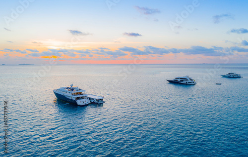 Aerial view of sunset and tourist ships in the Indian ocean with a small island on the horizon