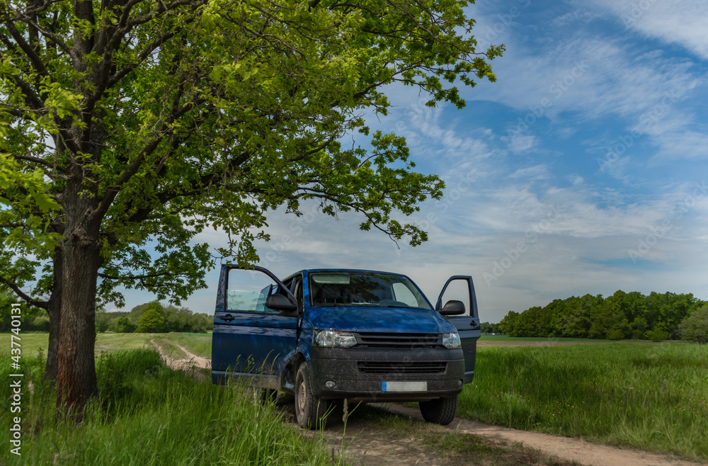 Blue big van on path in green spring nature Blue big van on path in green spring nature