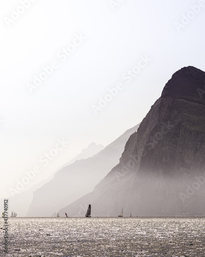 View of the Lago di Garda with fog, high mountains, surfs and boats