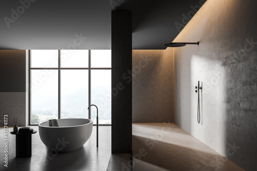 Bathtub and shower in grey concrete bathroom interior with window