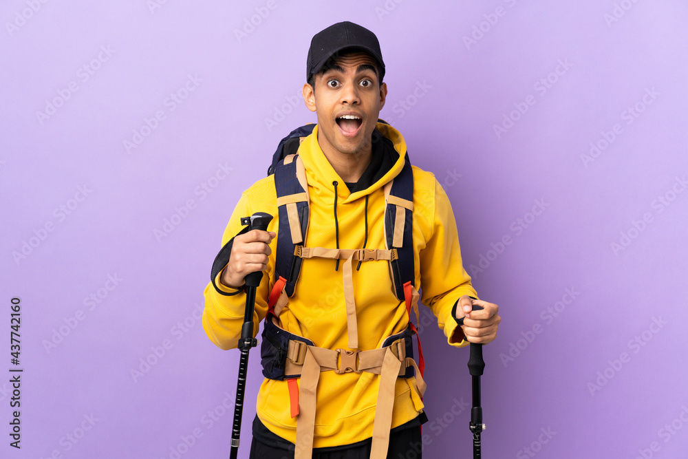 African American man with backpack and trekking poles over isolated background with surprise facial expression African American man with backpack and trekking poles over isolated background with surprise facial expression