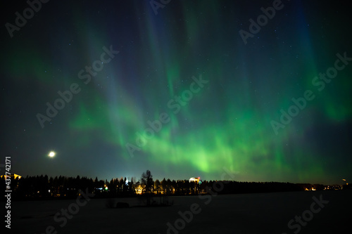 A various colour geomagnetic Northern Lights on the starry night sky over a city. Aurora Borealis over Swedish lake Islands. Northern Sweden