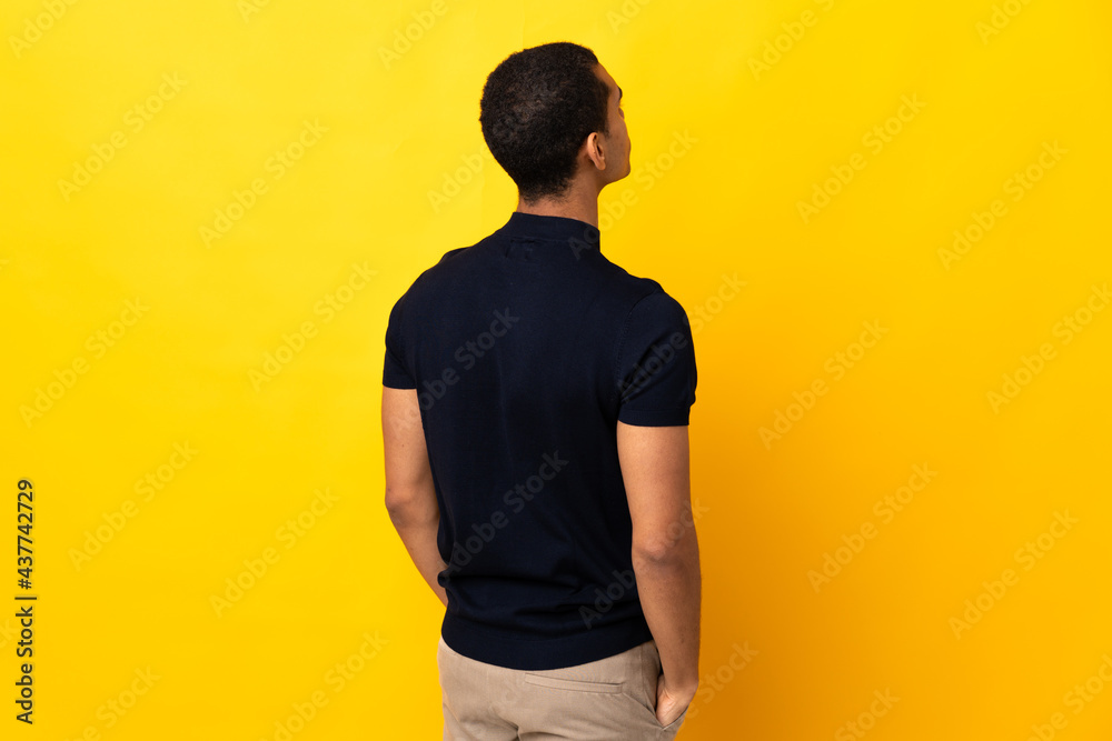African American man over isolated background in back position and looking back African American man over isolated background in back position and looking back