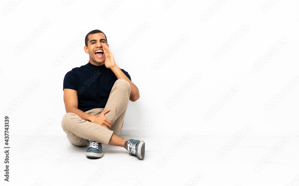 African American man sitting on the floor shouting with mouth wide open