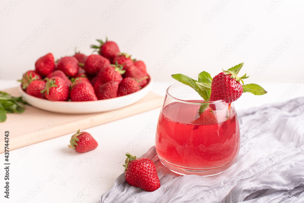 Glass with strawberry lemonade and strawberries on a table with textiles on a white background, summer drinks concept. Glass with strawberry lemonade and strawberries on a table with textiles on a white background, summer drinks concept.