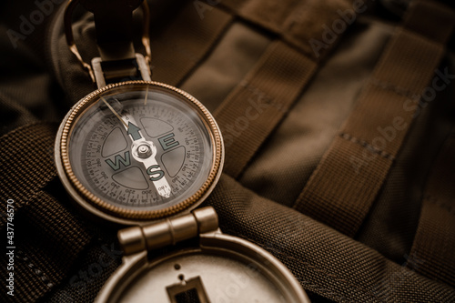 golden compass on tactical or travel backpack, shallow DOF, focus on dial. Concept for direction, travel, guidance or assistance.
