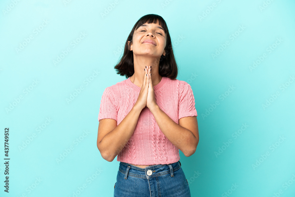 Young mixed race woman isolated on blue background keeps palm together. Person asks for something Young mixed race woman isolated on blue background keeps palm together. Person asks for something