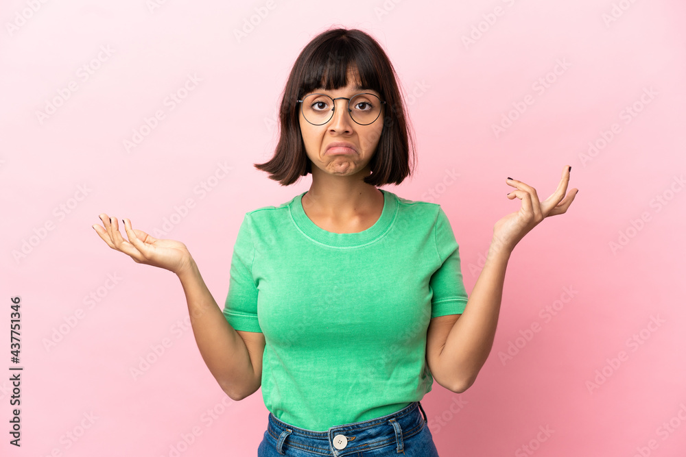 Young mixed race woman isolated on pink background having doubts while raising hands Young mixed race woman isolated on pink background having doubts while raising hands