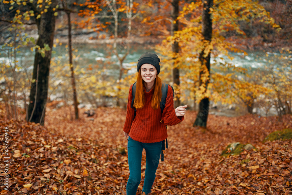 woman hiker with backpack in autumn forest near mountain river and fallen leaves woman hiker with backpack in autumn forest near mountain river and fallen leaves