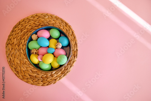 Colorful easter eggs in bowl, pink background