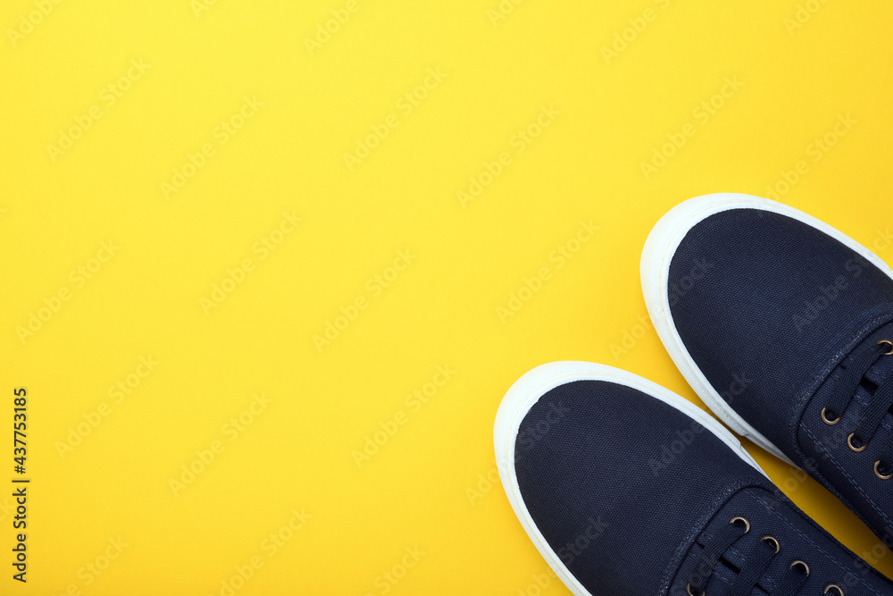 Blue pair of sneakers gym shoes on a yellow background. View from above. Blue pair of sneakers gym shoes on a yellow background. View from above.