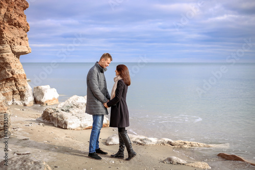 Happy young couple stands on the shore of the snowy sea. Winter