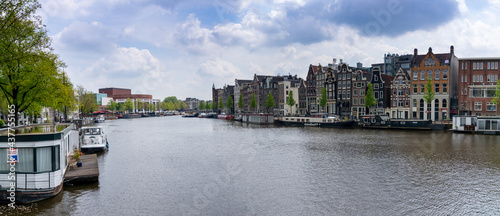 panorama cityscape view of Amsterdam with many historic buildings lining the sides of the Amstel canal