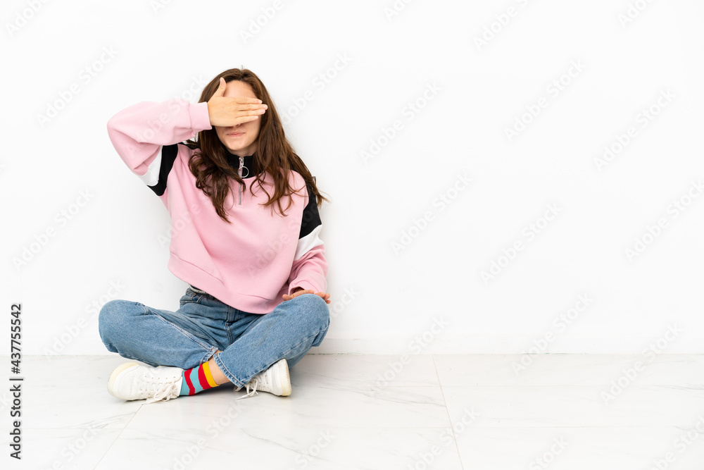 Young caucasian woman sitting on the floor isolated on white background covering eyes by hands. Do not want to see something Young caucasian woman sitting on the floor isolated on white background covering eyes by hands. Do not want to see something