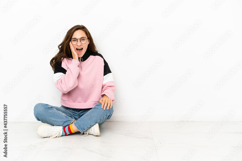 Young caucasian woman sitting on the floor isolated on white background with surprise and shocked facial expression Young caucasian woman sitting on the floor isolated on white background with surprise and shocked facial expression