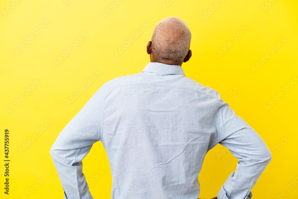 Cuban Senior isolated on yellow background in back position Cuban Senior isolated on yellow background in back position