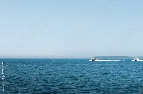 Fototapeta Naklejka Na Ścianę i Meble -  Landscape shot of a white motor boat moving fairly quickly on a blue ocean in Bruce Peninsula, Ontario, Canada.