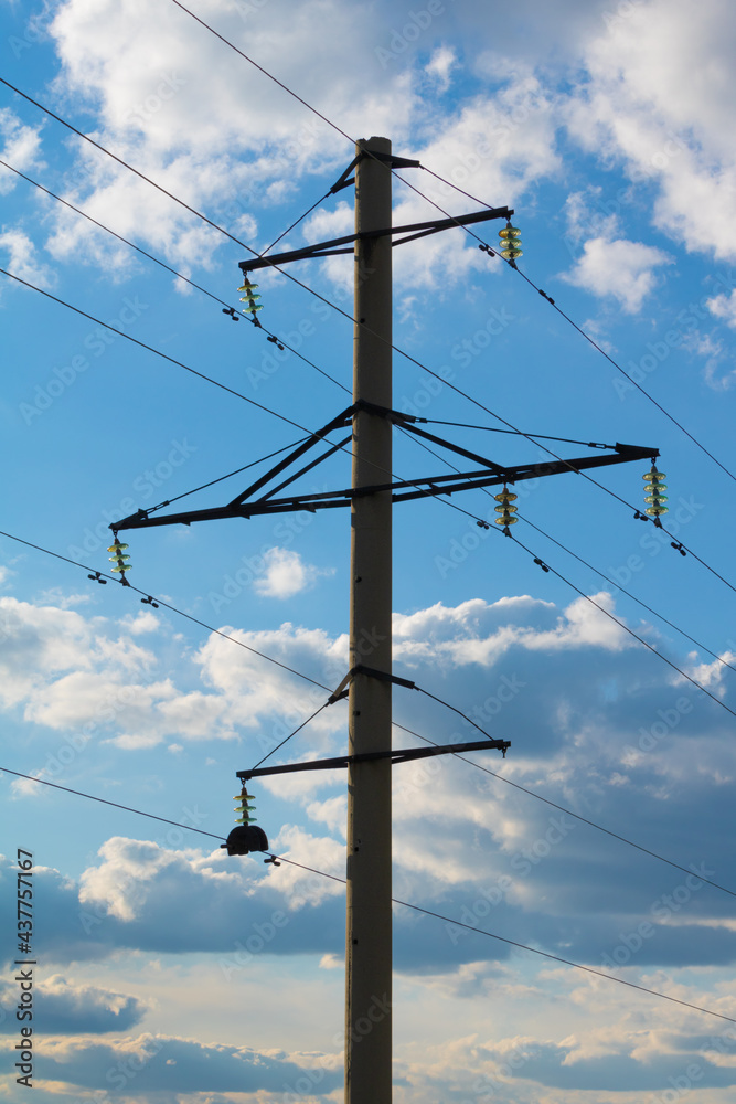 Concrete tower of power lines against the background of a blue sky with clouds Concrete tower of power lines against the background of a blue sky with clouds