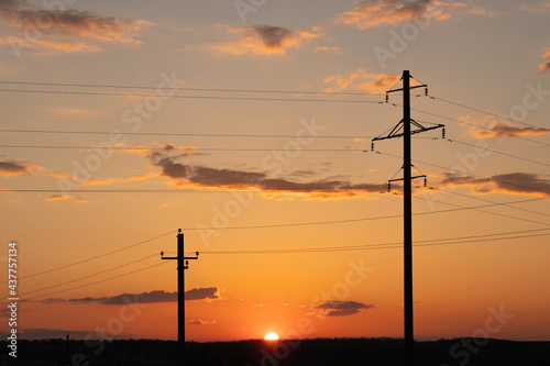 Two concrete poles of power lines on a sunset background