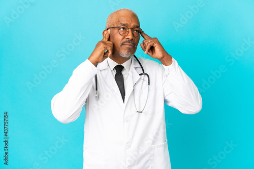Senior doctor man isolated on blue background having doubts and thinking