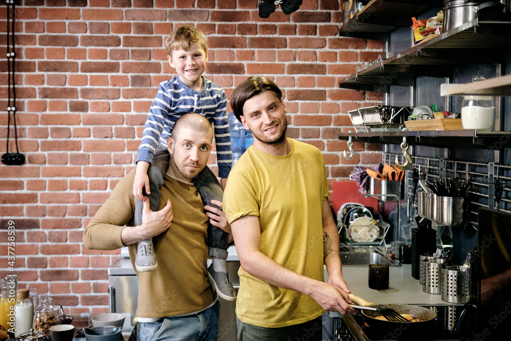 Two young males and their cute son cooking in the kitchen