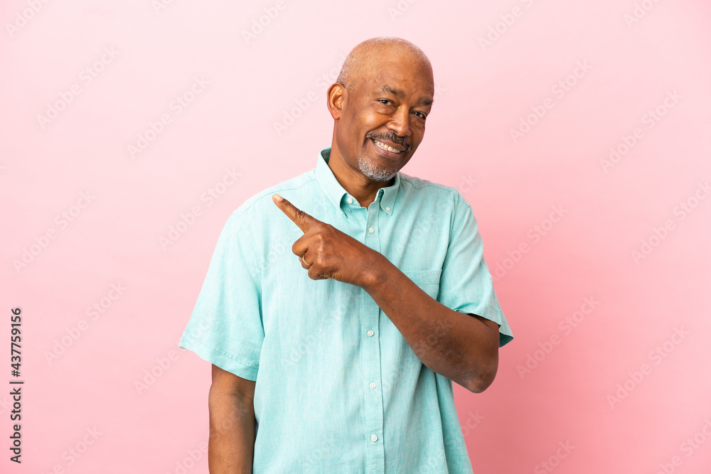 Cuban senior isolated on pink background pointing to the side to present a product Cuban senior isolated on pink background pointing to the side to present a product