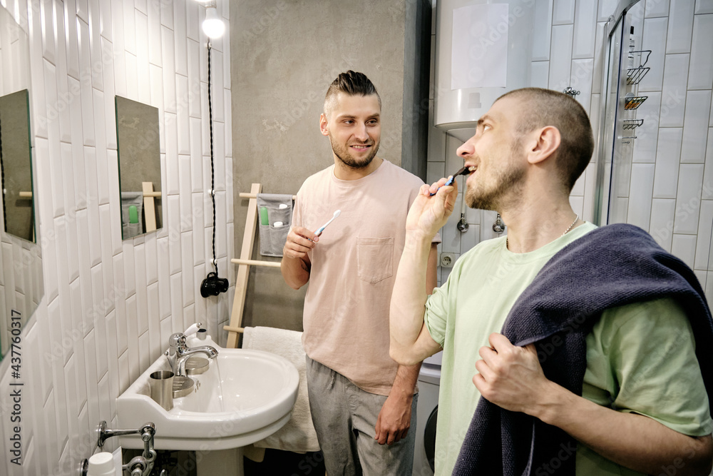Two young gay men brushing teeth in bathroom in the morning Two young gay men brushing teeth in bathroom in the morning
