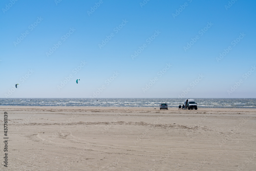 van life kite surfers parked on a golden beach next to the ocean