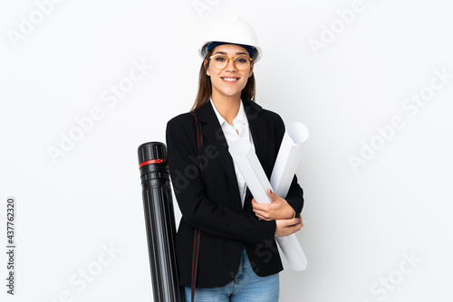 Young architect caucasian woman with helmet and holding blueprints over isolated background laughing photo
