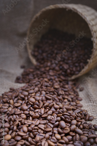 Coffee beans spilling out of the basket onto the surface covered with a jute sack