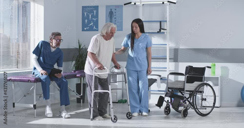 Male and female doctors helping senior man to stroll with walking frame Male and female doctors helping senior man to stroll with walking frame