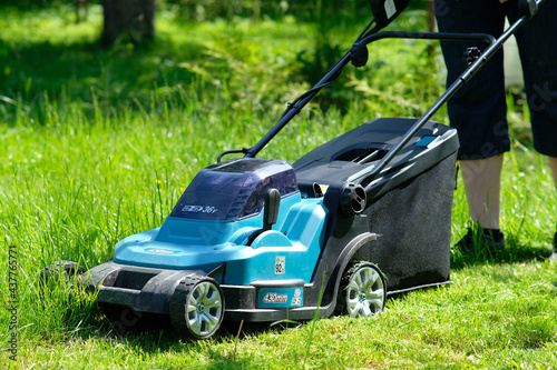Electric lawn mower on the green grass, garden equipment.