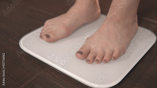 The girl gets on the scales. Weighing on scales. Close-up of female legs on the scales. Excess weight check
