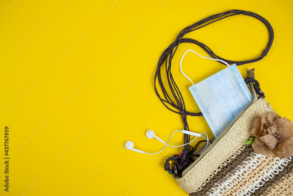 Straw bag, protection mask and headsets on yellow background. Vacation concept. Top view, copy space Straw bag, protection mask and headsets on yellow background. Vacation concept. Top view, copy space