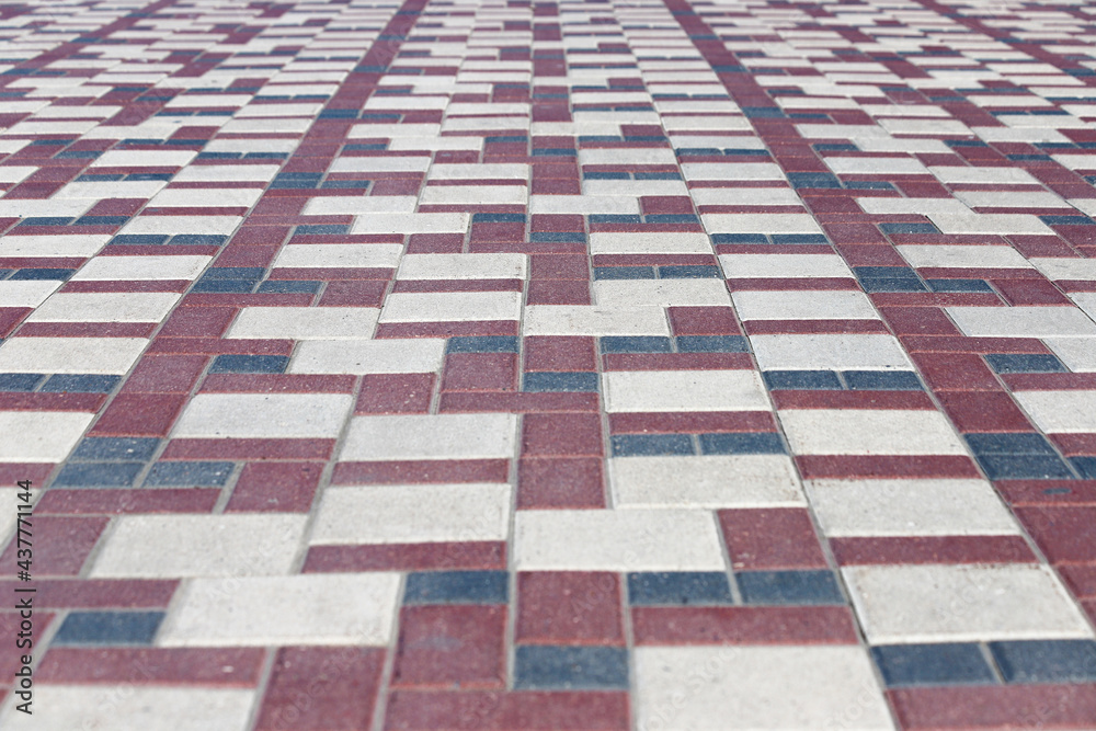 Sidewalk paved with rectangular red, white and gray tiles in perspective