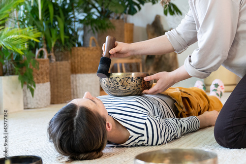 Young female having tibetan massage, singing bowl therapy with traditional tibet cymbals at home. Caucasian woman relax with alternative buddhism medicine. Wellbeing, wellness, stress relief concept