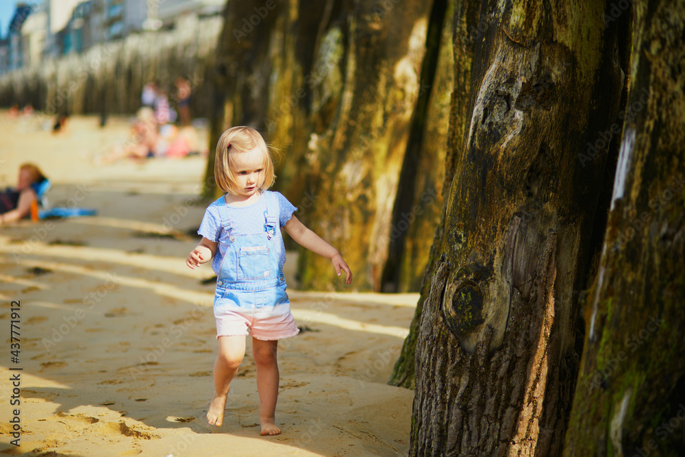 Adorable toddler girl having fun on Sillon beach in Saint-Malo, Brittany, France Adorable toddler girl having fun on Sillon beach in Saint-Malo, Brittany, France