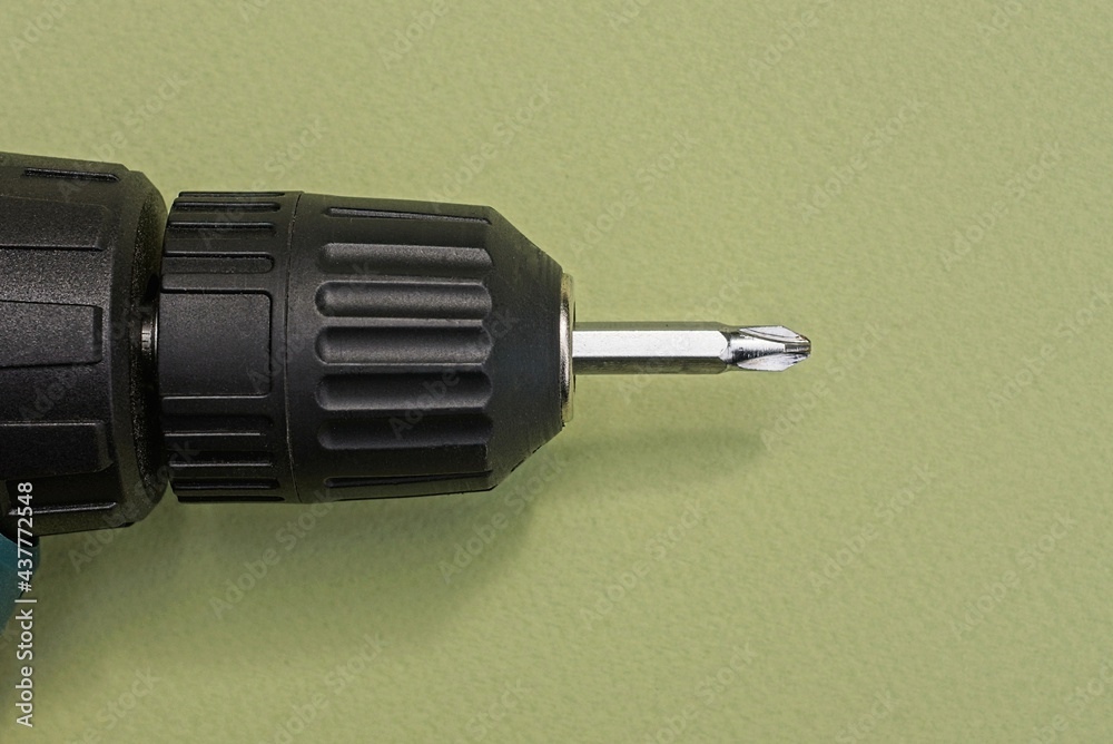 one big black compact electric screwdriver lies on a green table one big black compact electric screwdriver lies on a green table