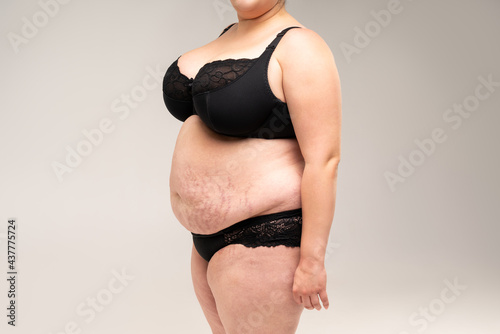Fat woman in black lingerie, overweight female body on gray background