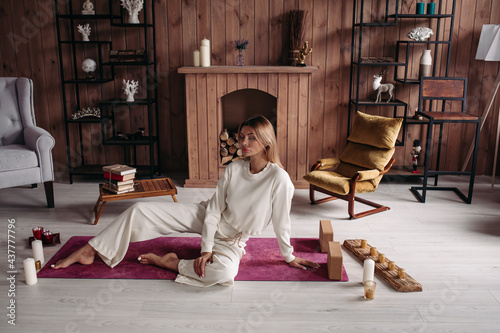 relaxed beautiful caucasian woman with fair hair in white clothes lies on the yoga mat with closed eyes