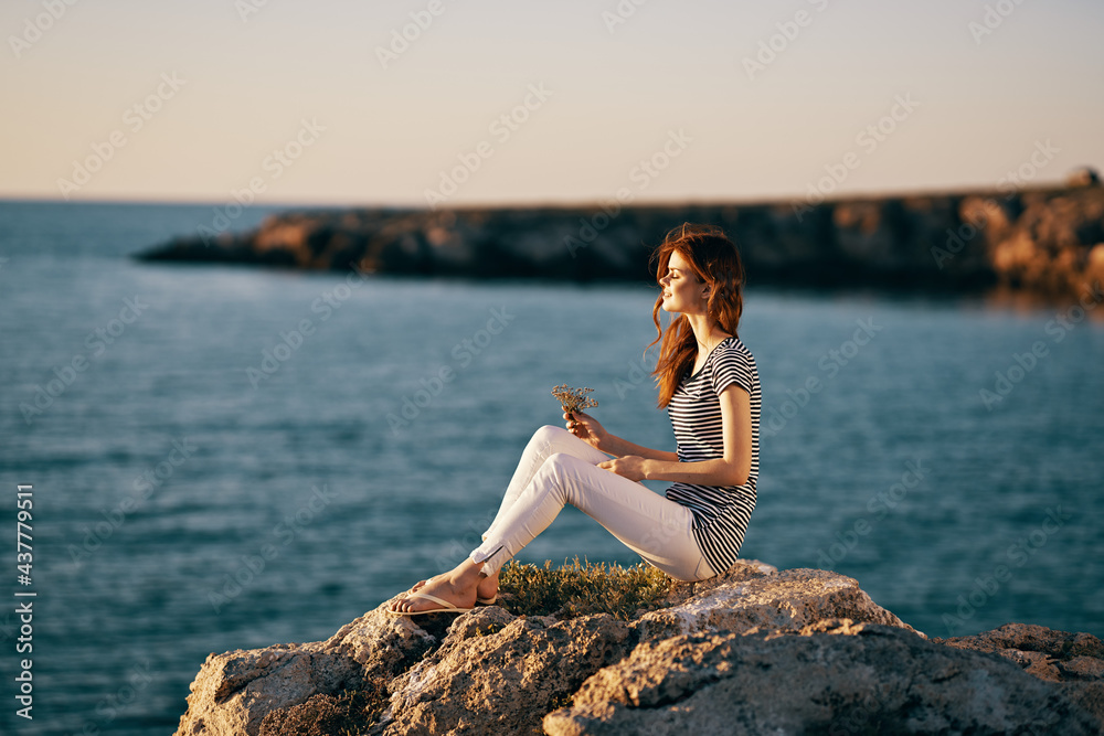 woman near the sea mountain on a large stone sea landscape sunset