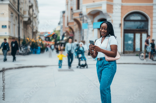 Cheerful african american woman using smartphone