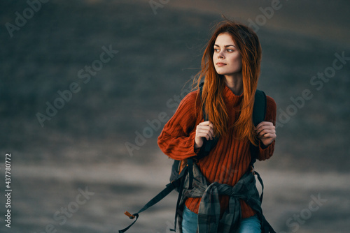 pretty woman travel hiking backpack on her back and red sweater