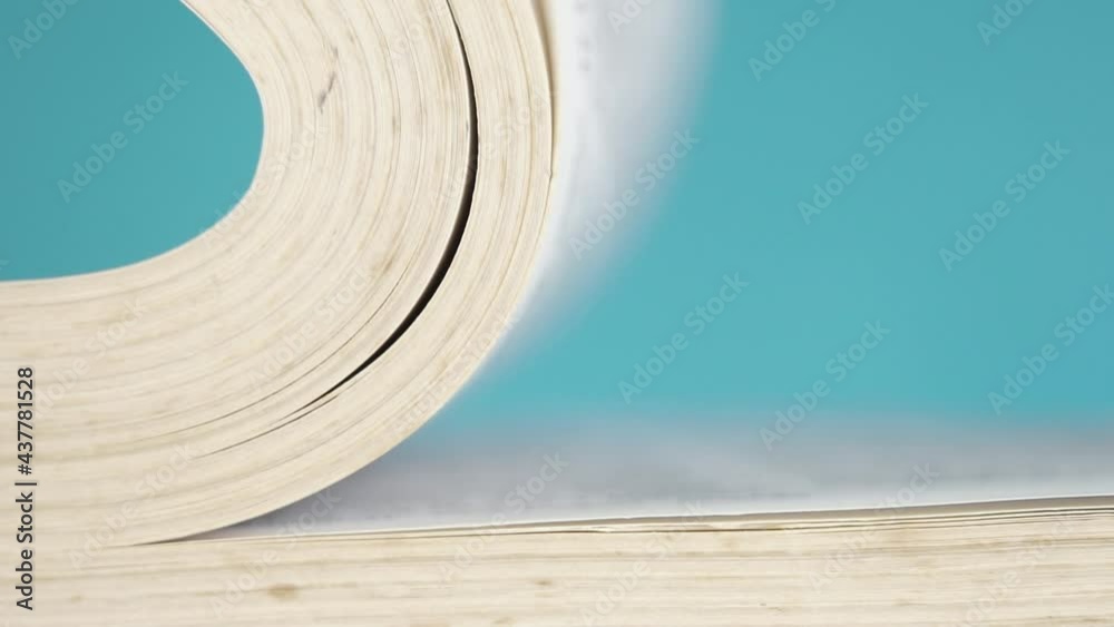 Close-up pages of a book falling and turning over in slow motion. On a colored blue background. Wisdom and learning concept. Blurred text. Selective focus. Macro shot Close-up pages of a book falling and turning over in slow motion. On a colored blue background. Wisdom and learning concept. Blurred text. Selective focus. Macro shot