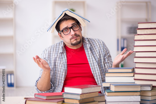 Young male student and too many books in the classroom