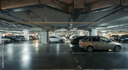 Underground public garage parking with cars in modern mall.