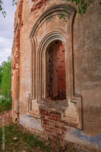 Close-up  a window with the remains of a lattice. An old abandoned church. In the background  a forest and a cloudy sky.