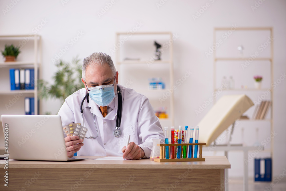 Old male doctor working in the clinic during pandemic Old male doctor working in the clinic during pandemic