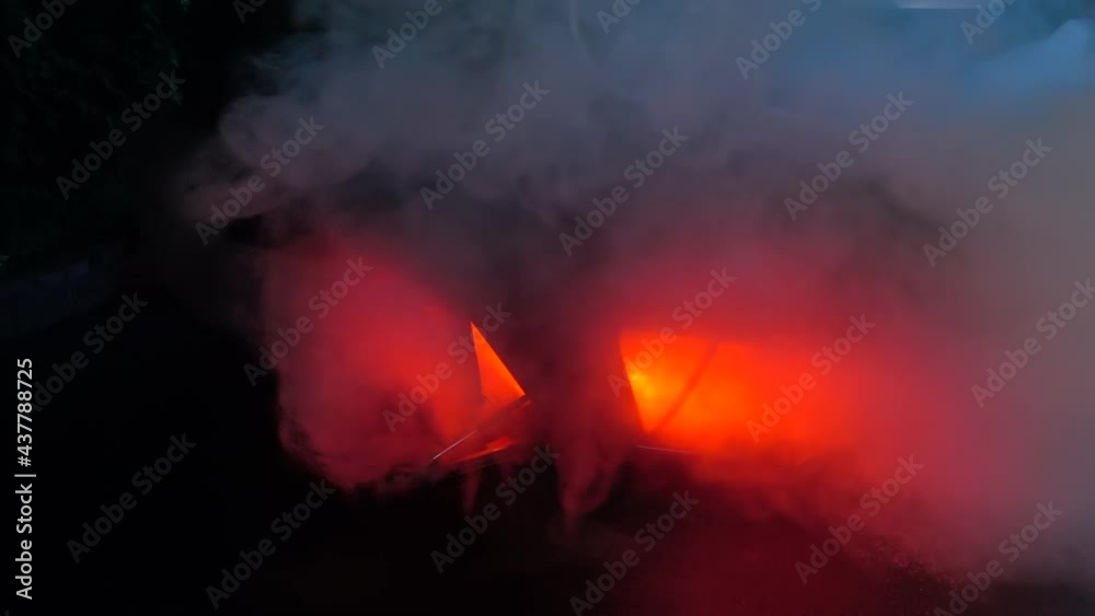 Car Crash Traffic Accident Scene: a burning, heavily smoking car after a road accident, inverted, lies on the street at night