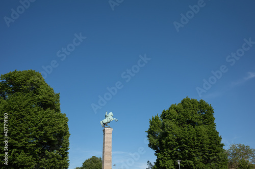 Outdoor sunny view of Ulanendenkmal, landmark statue and treetop on promenade riverside of Rhine River in Düsseldorf, Germany in summer season.